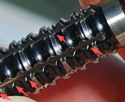 Grooved tungsten alloy part with burrs on the groove edges, marked by arrows